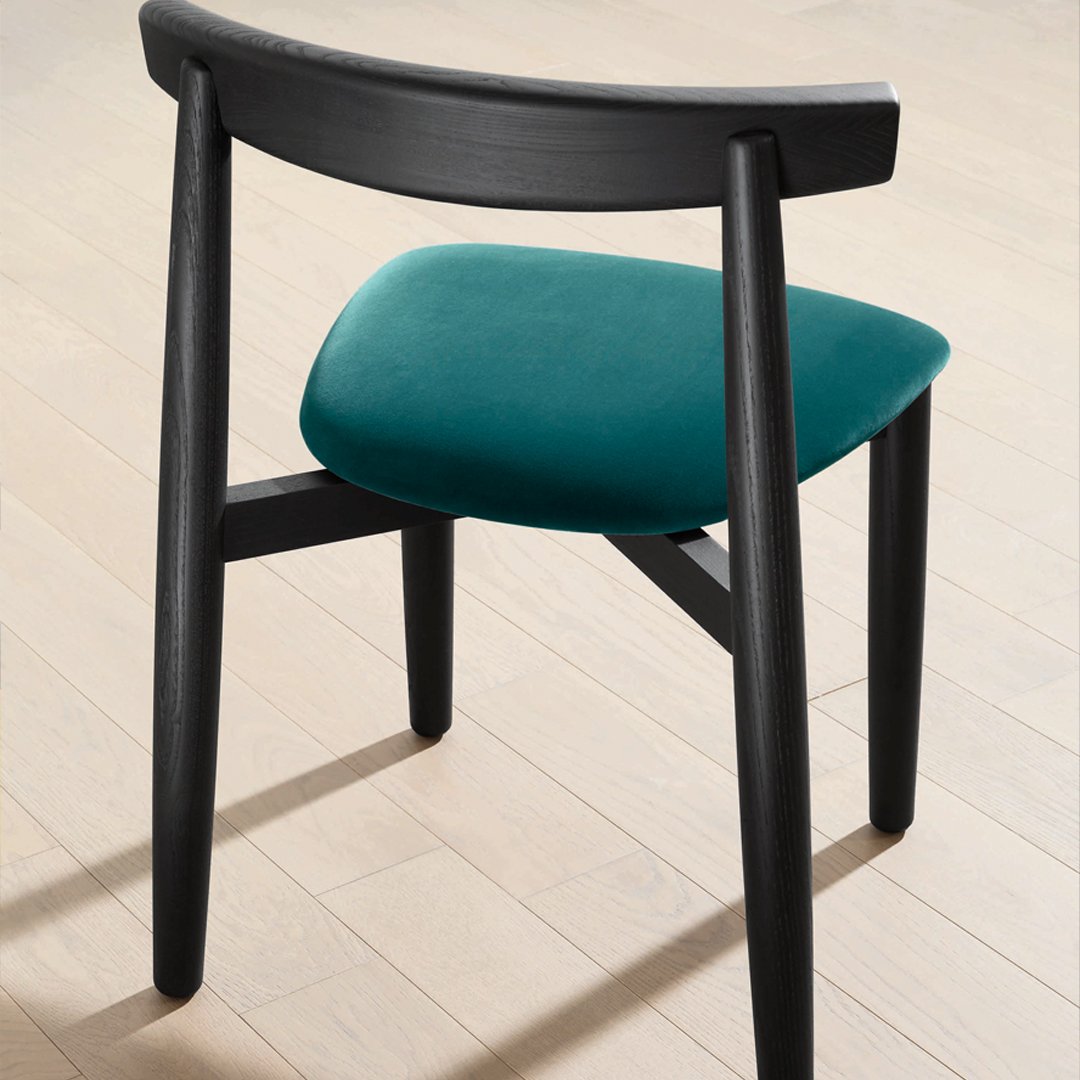 Teal velvet chair cushion with sleek black wooden legs, showcasing a modern design and contrasting colors.