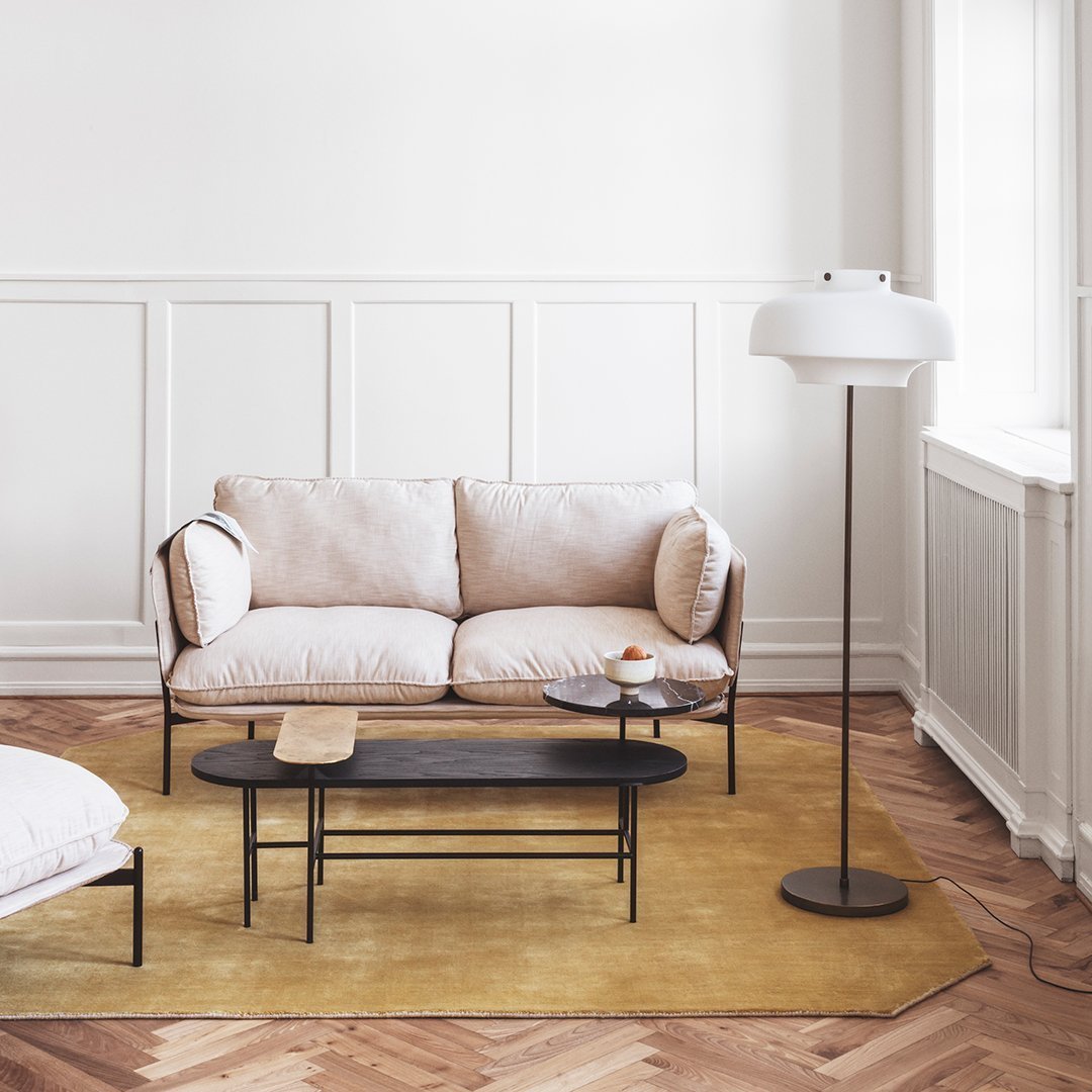 Light beige sofa on a warm yellow rug, complemented by a sleek black coffee table and light-toned wooden accents.