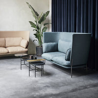 "Light blue sofa with plush cushions, beige accent sofa, and black metal coffee table on a gray floor."