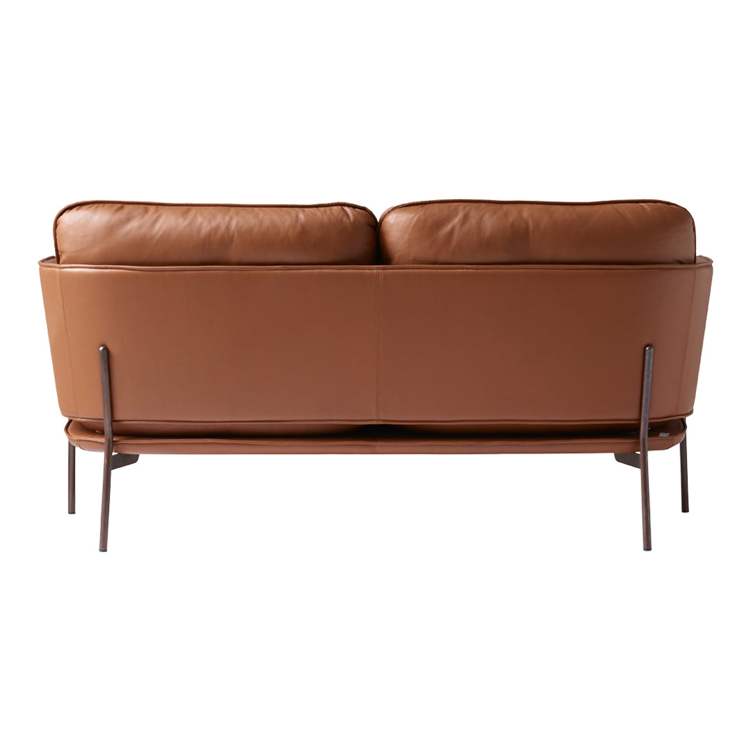Brown leather sofa with smooth texture and minimalist metal legs, showcasing a sleek, modern design.