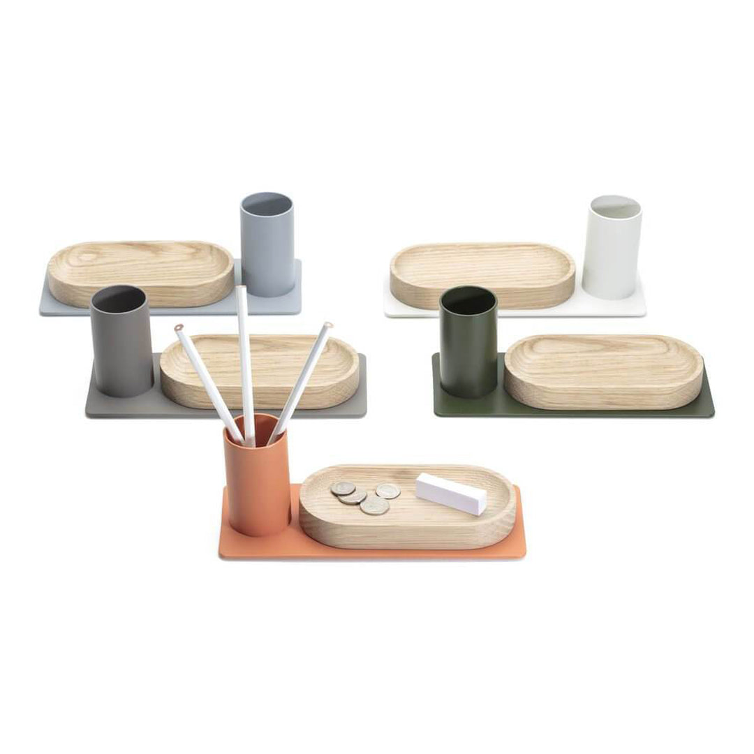 Five stylish trays in muted colors with bamboo accents, featuring various cylindrical containers and sleek patterns.