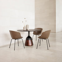 Elegant round table with a brown and black base, complemented by chic brown chairs in a minimalist space.
