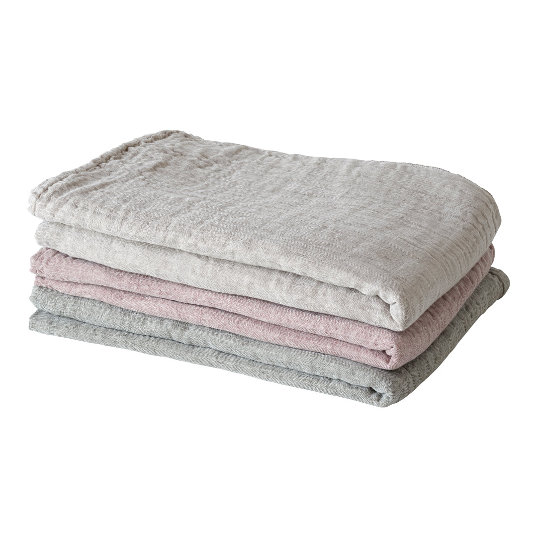 Stack of soft blankets in light gray, blush pink, and cream with a textured, cozy pattern. Perfect for any home decor.