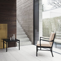 Black lounge chair with beige cushion and minimalist black table in a modern, neutral-toned interior.