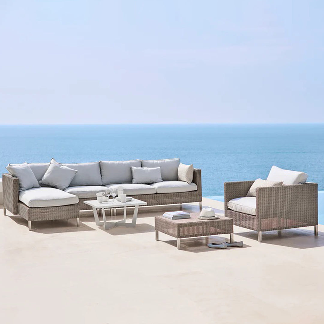"Light gray outdoor sofa set with white cushions and beige wicker detailing, perfect for coastal decor."