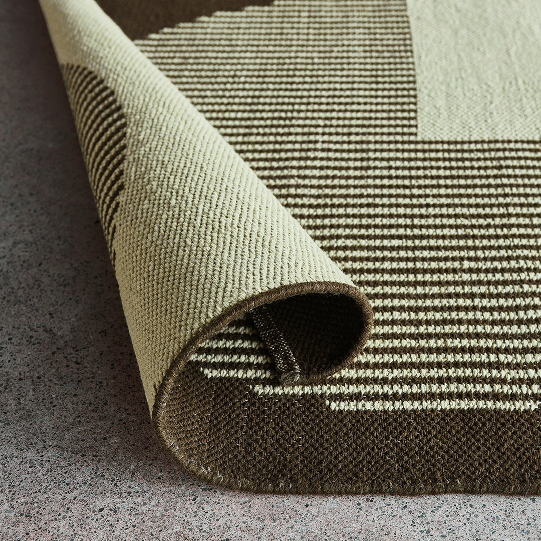 Beige and brown patterned rug with textured stripes, showcasing a modern design and rolled edge.