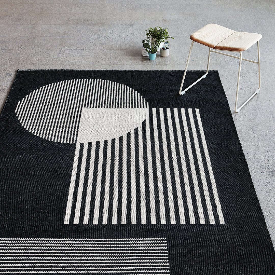 Black and white geometric rug featuring stripes and circular patterns, perfect for modern home decor.