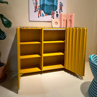 Bright yellow cabinet with ribbed texture and vibrant patterns, featuring multiple open shelves and colorful accents.