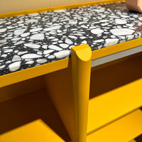 Yellow storage unit with a black and white speckled top, showcasing modern patterns and vibrant color contrast.