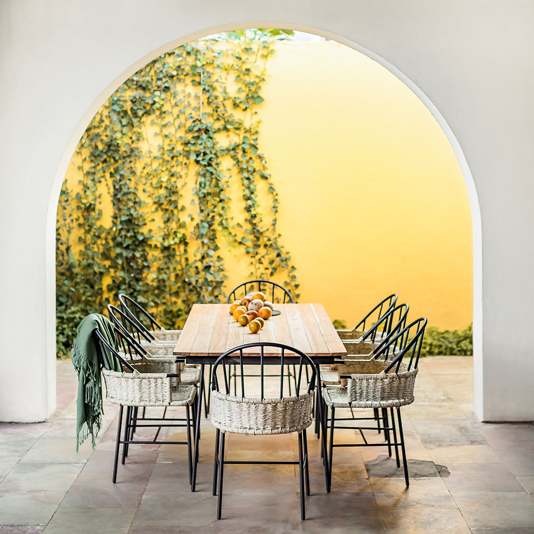 "Stylish black and natural woven dining chairs surrounding a rustic wooden table, framed by a vibrant yellow backdrop."
