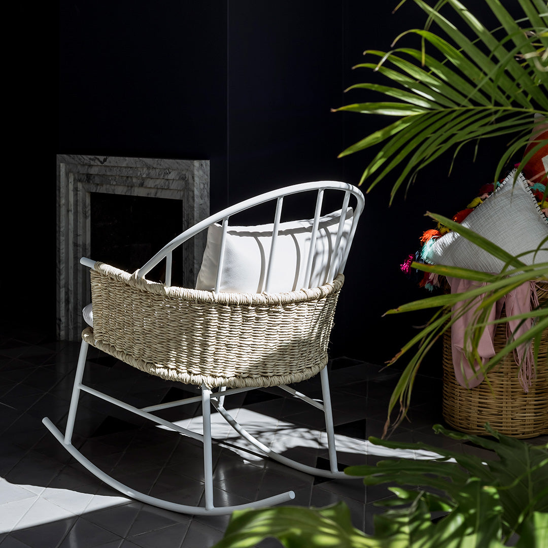 Modern wicker rocking chair with a silver frame, featuring a natural woven pattern and a white cushion.