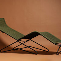 Olive green woven lounge chair with a modern black frame against a warm brown backdrop. Stylish and functional design.