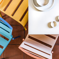 Colorful chairs in yellow, blue, and peach with striped patterns, arranged around a modern table with minimalist decor.