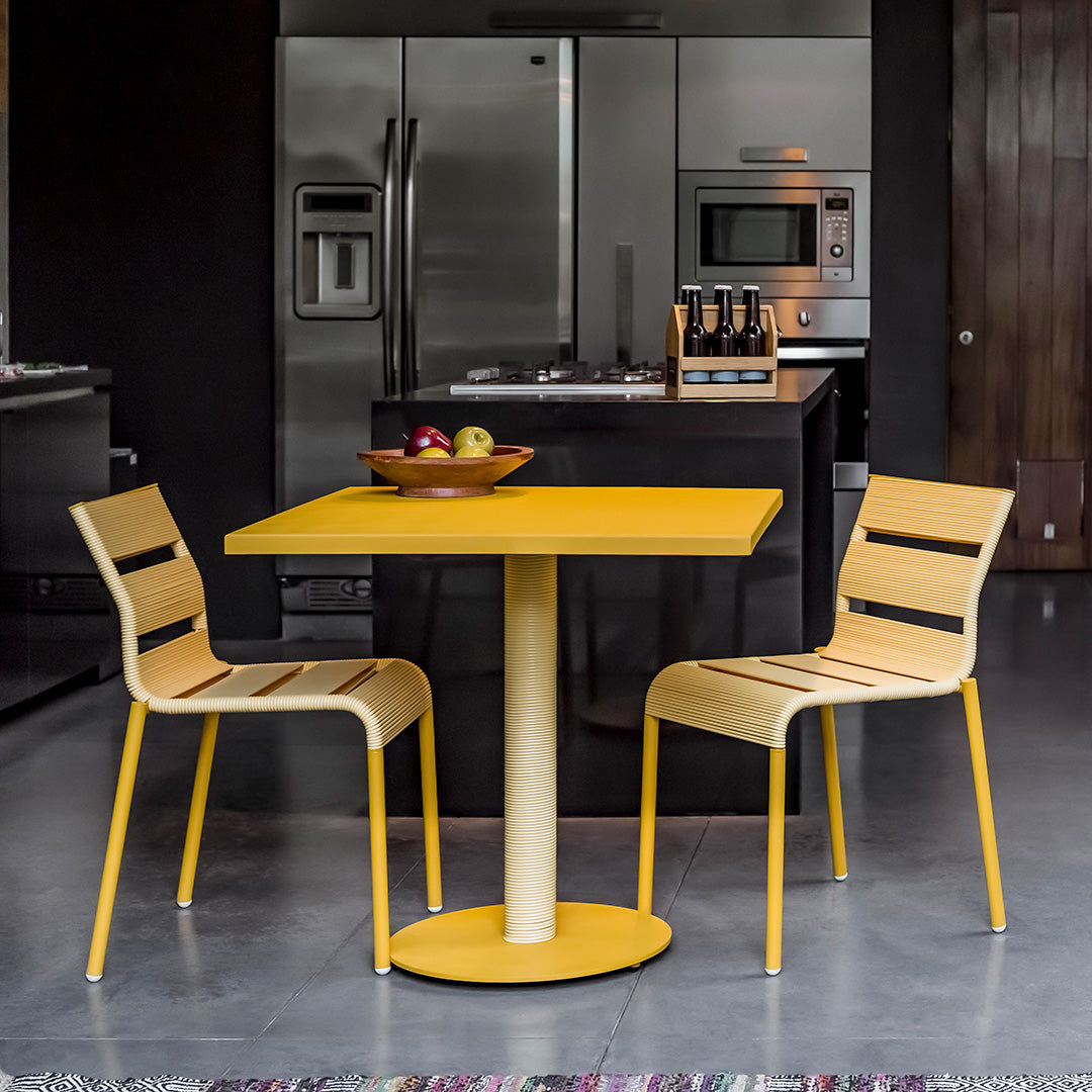 Bright yellow table with natural wood chairs, featuring sleek lines and a modern design in a contemporary kitchen setting.