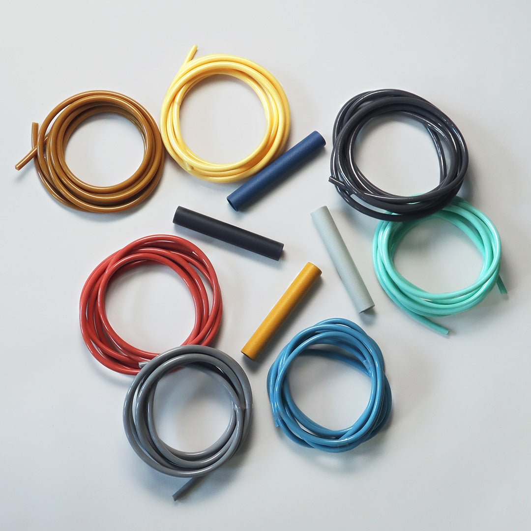Colorful assortment of coiled wires in yellow, blue, black, teal, gray, red, and orange on a light background.