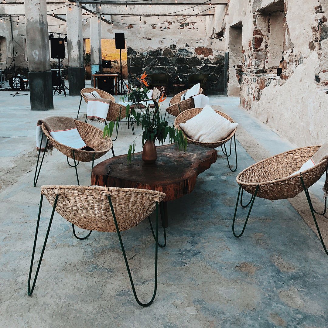 Woven rattan chairs with natural patterns, earthy tones, and modern metal legs against a textured concrete floor.