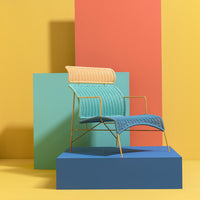 Colorful chair in teal, gold, and blue, set against vibrant yellow, pink, and green geometric backgrounds.