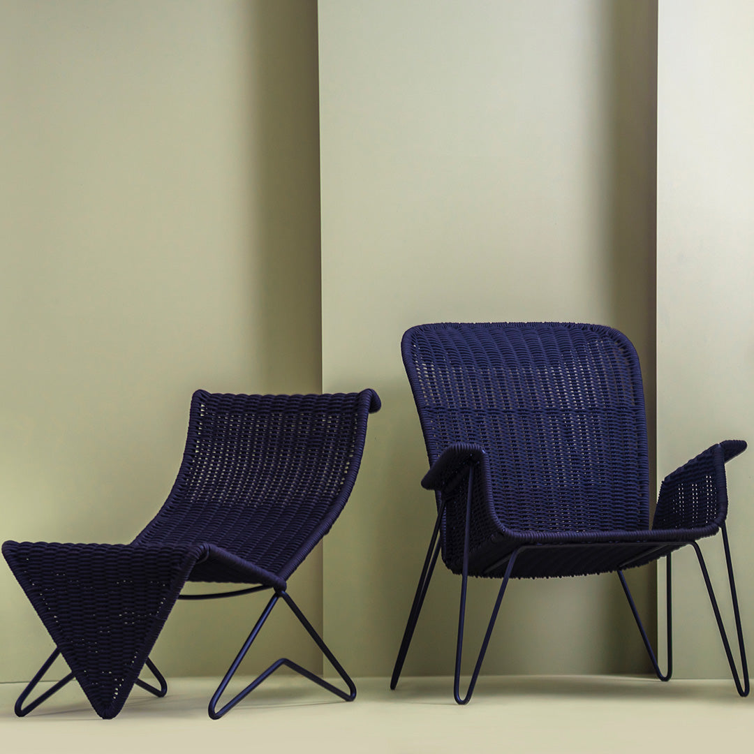 Navy blue patio chairs with sleek lines and textured patterns against a soft green background.