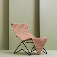 Peach woven lounge chair with geometric pattern against soft green backdrop. Modern design aesthetics highlighted.
