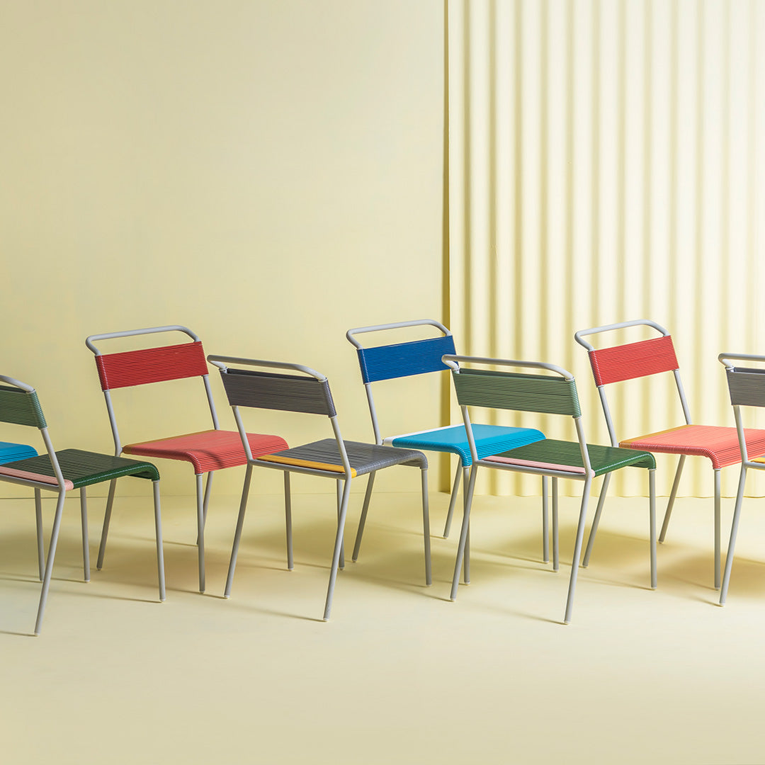 Colorful modern chairs in red, blue, green, and gray, featuring a sleek design and stylish patterns on seats.