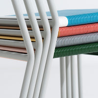 Stacked chairs featuring vibrant colors: blue, red, green, grey, gold, and white, with a sleek striped pattern.