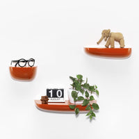 "Bright orange shelves with minimalist design, featuring smooth curves and a glossy finish, set against a white backdrop."