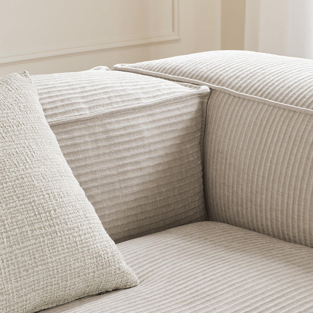 Textured beige sofa with subtle striped patterns and a woven, solid-color pillow for a cozy, neutral look.