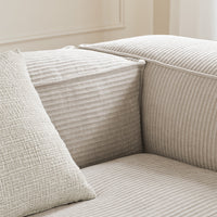 Textured beige sofa with subtle striped patterns and a woven, solid-color pillow for a cozy, neutral look.