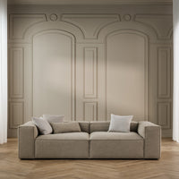 Beige modular sofa with textured fabric and minimalist design, set against a neutral wall with elegant molding.