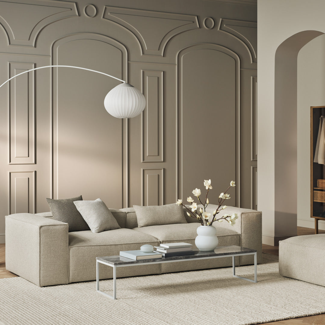 Beige and gray sofa with minimalist design, neutral color palette, and subtle textures against a light-colored wall.