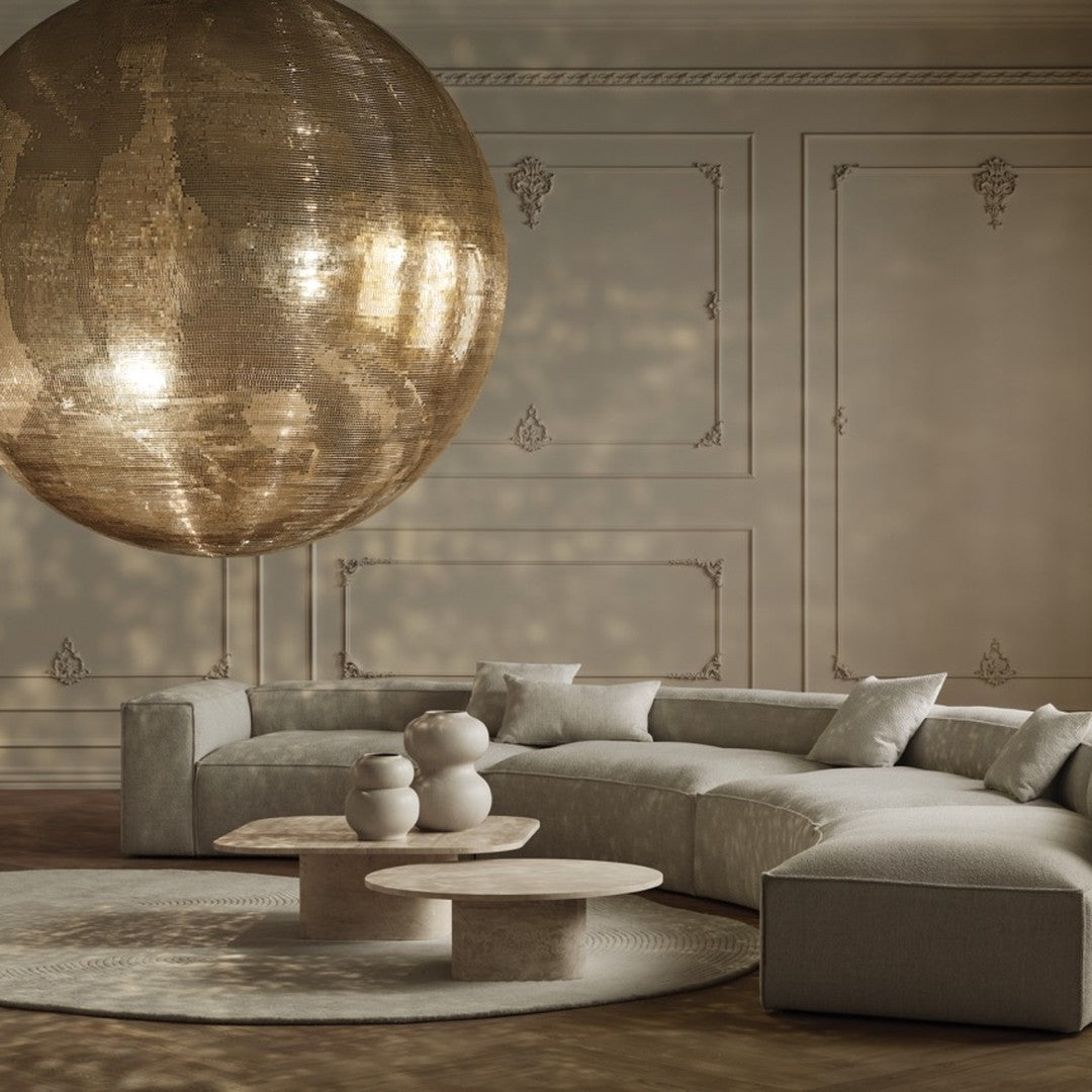 Sleek beige curved sofa with muted gray accent pillows, elegant round coffee tables, and a golden globe pendant light.