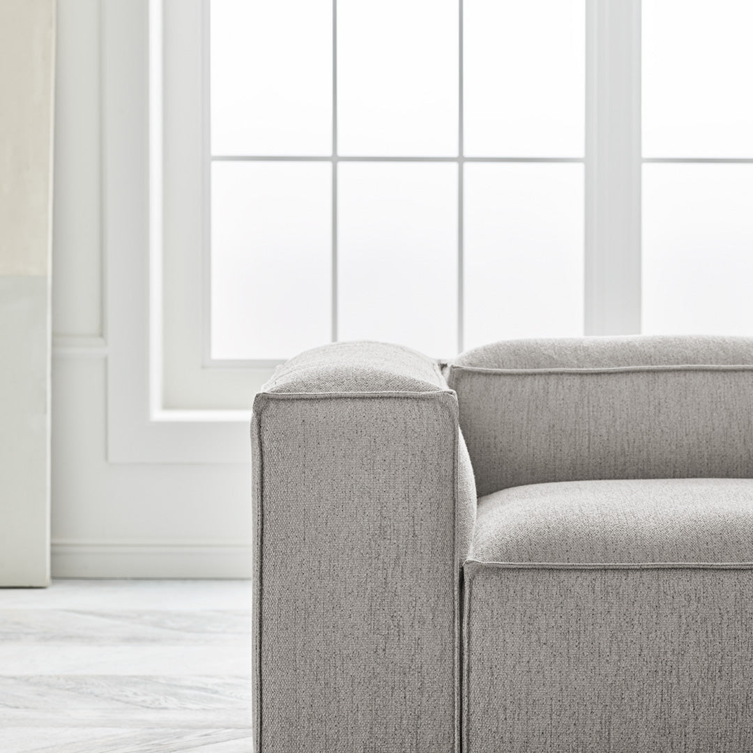 Light gray fabric sofa with a subtle textured pattern, complementing a bright, modern interior.