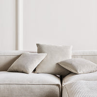 Light gray decorative pillows on a striped light gray sofa, creating a subtle and modern aesthetic.