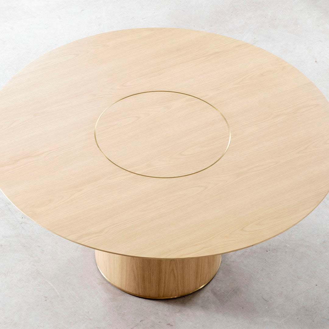 Light oak round table with a subtle grain pattern and a gold accent in the center. Elegant and modern design.