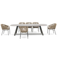 Modern oval dining table with a light gray finish and six beige woven chairs for a stylish look.