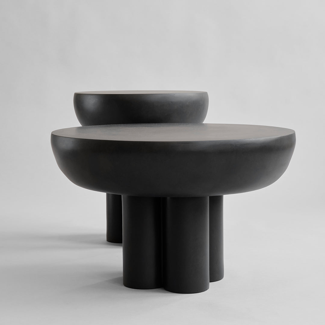 Black round tables with smooth surfaces and geometric bases, showcasing a modern, minimalist design.