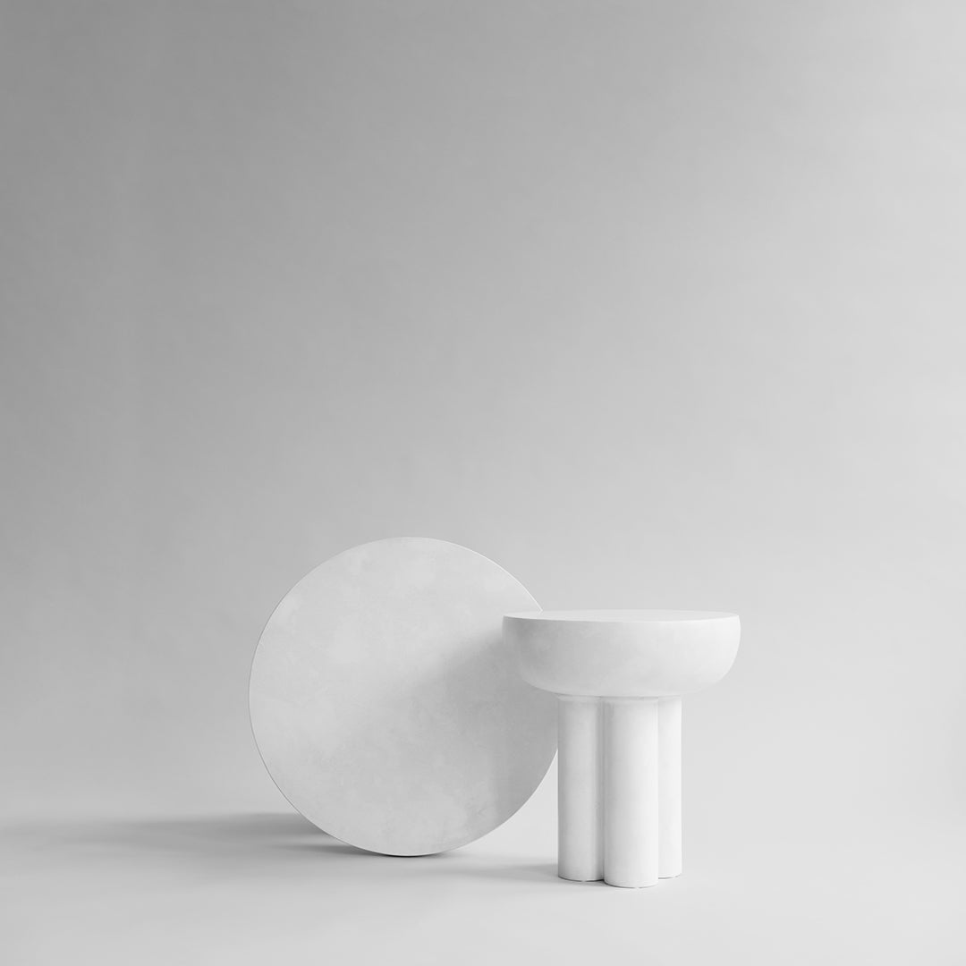 Minimalist white decor featuring a circular plate and a bowl with smooth, clean lines against a light gray background.