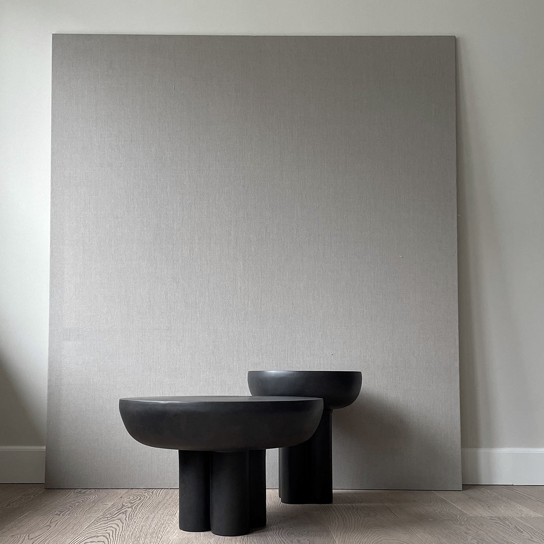 Black textured vases with smooth, rounded edges against a subtle gray background, adding modern elegance to any space.