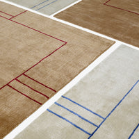 Abstract beige and tan rugs featuring red and blue geometric patterns. Perfect for modern decor.