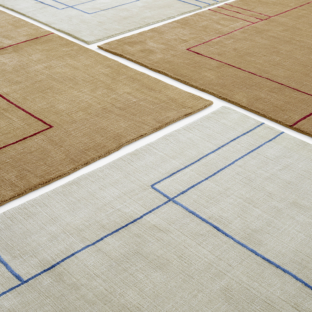 Neutral rugs with geometric patterns in tan, cream, and bold red and blue outlines. Ideal for modern interiors.