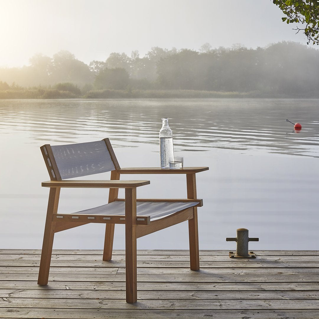 Wooden outdoor chair with gray slatted seat and backrest, set against a serene waterfront background.
