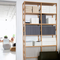 "Natural wood shelving unit displaying white, gray, and beige storage boxes in a modern, minimalist interior."