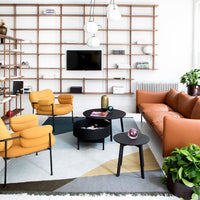 Modern living room featuring mustard yellow chairs, a brown sofa, geometric area rug in teal, gray, and beige patterns.