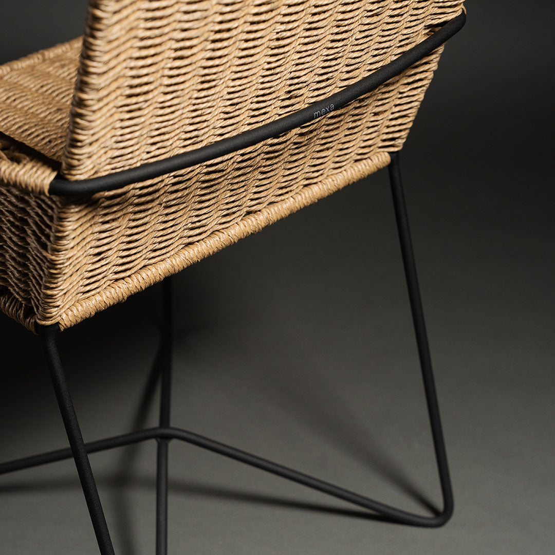"Woven rattan chair in natural tan with sleek black metal legs, featuring a modern minimalist design."