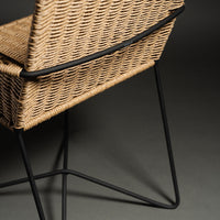 "Woven rattan chair in natural tan with sleek black metal legs, featuring a modern minimalist design."