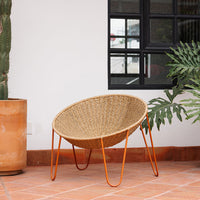 Natural woven pattern in beige with bold orange legs, complementing a minimalist indoor setting. Perfect for modern decor.