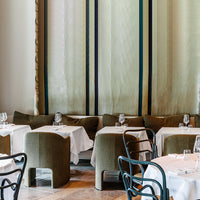 Elegant green curtains with blue stripes, complemented by neutral-toned seating and crisp white tablecloths.