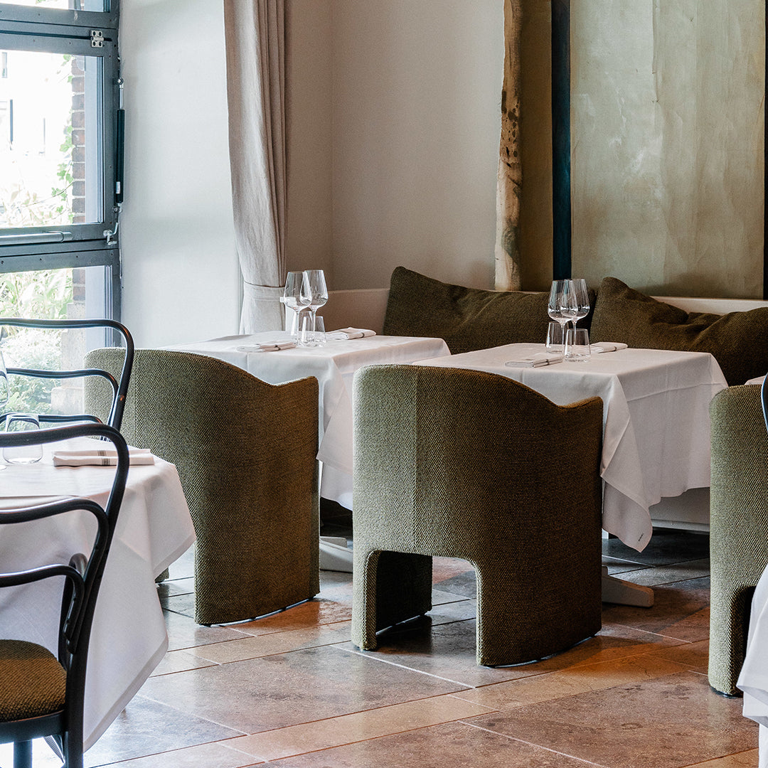 "Elegant restaurant setting with olive green chairs and crisp white tablecloths, featuring soft neutral tones."