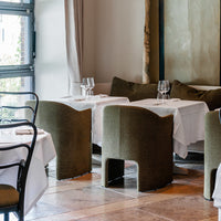 "Elegant restaurant setting with olive green chairs and crisp white tablecloths, featuring soft neutral tones."
