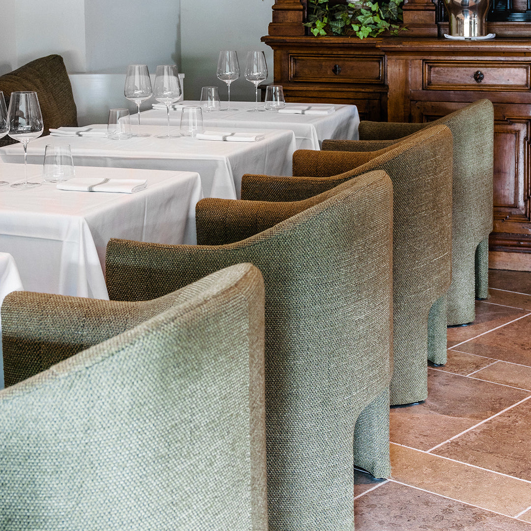 "Stylish green upholstered chairs with textured fabric, arranged around white tablecloths in an elegant dining setting."